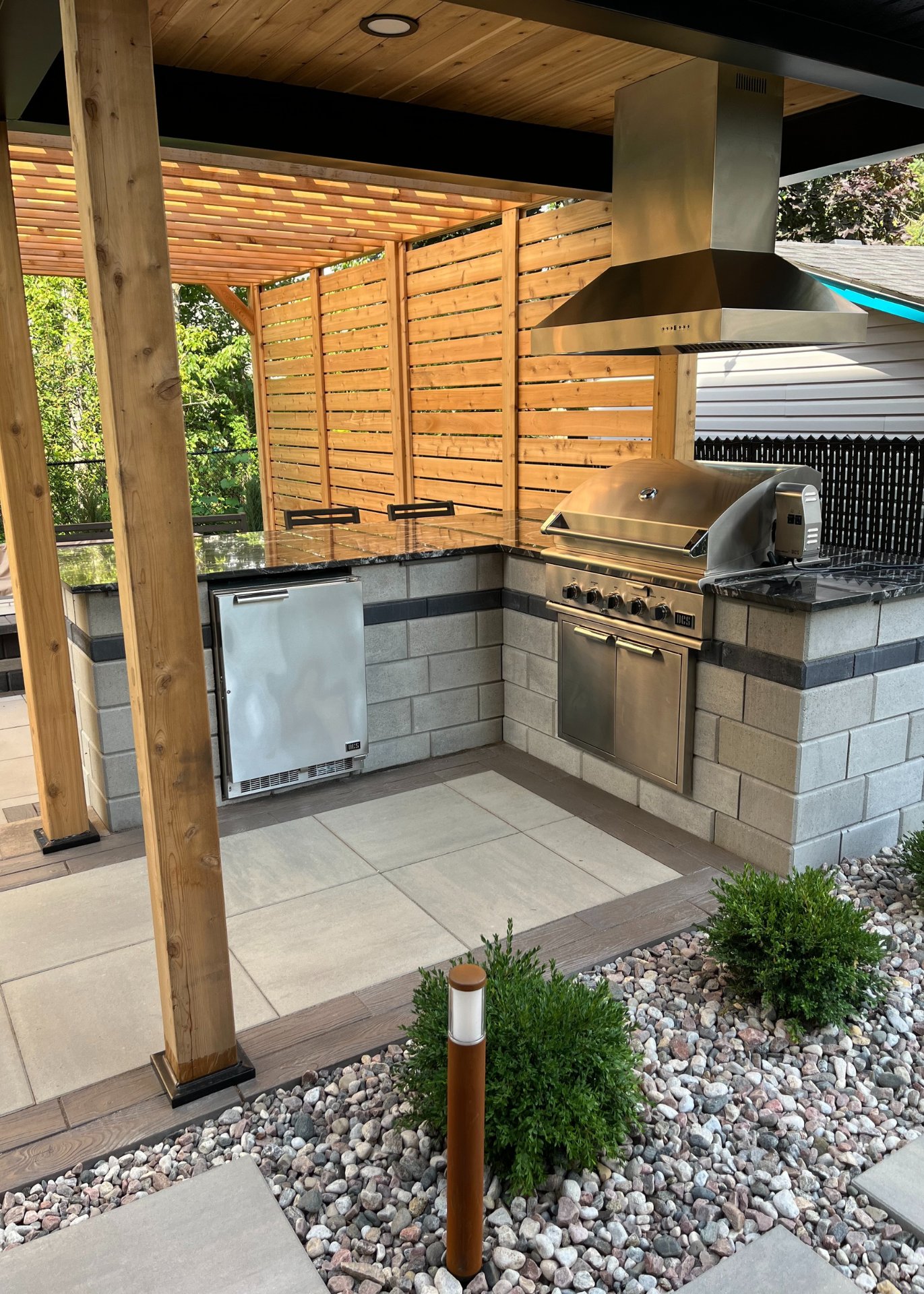 Corner of outdoor kitchen with oven, bbq and ventilation.